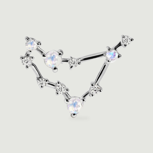 A silver stud is pictured close up, revealing the polished bars and small prong settings around its pale gemstones.