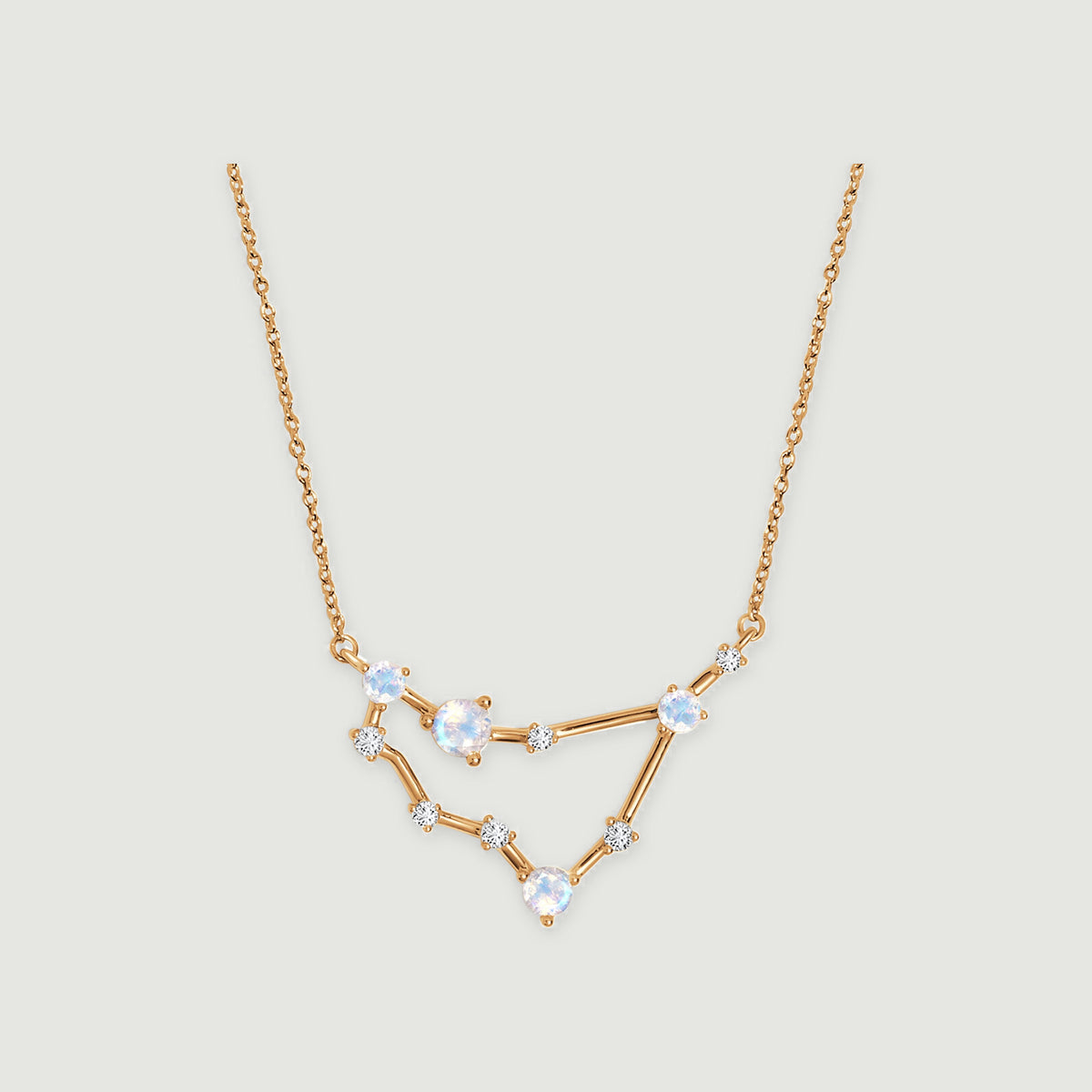 A yellow gold necklace with an angular open pendant, four round iridescent stones, and small clear accents.