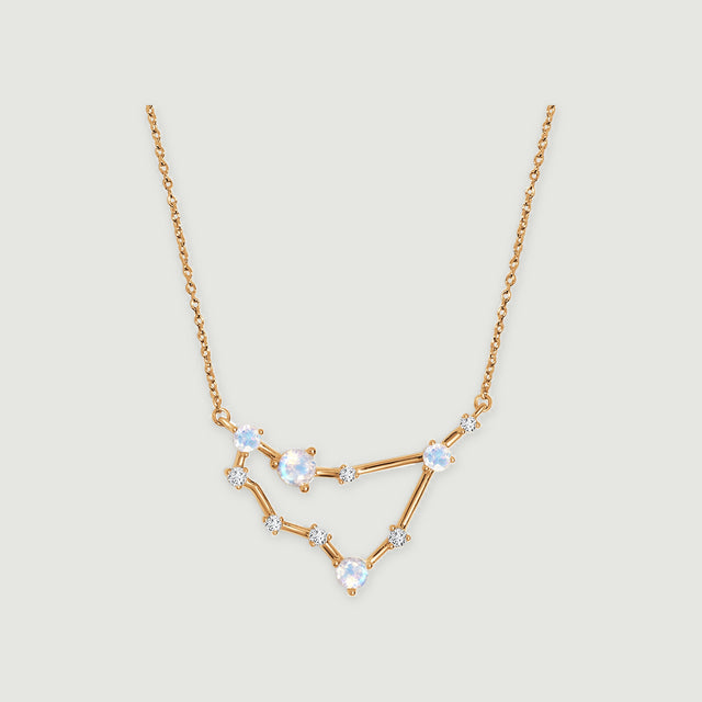 A yellow gold necklace with an angular open pendant, four round iridescent stones, and small clear accents.
