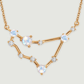 Four pale round stones sit along the yellow gold bars of a geometric pendant.