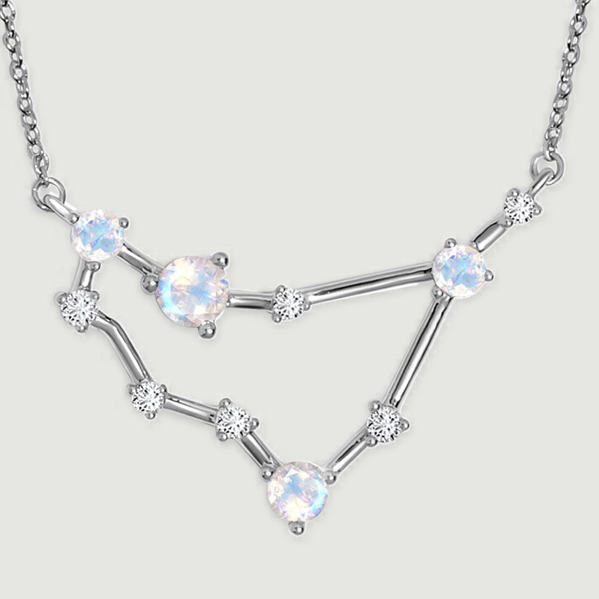 The silver pendant has polished connecting bars and small clear stones between its larger round stones.