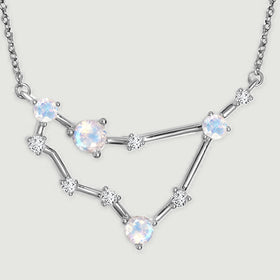 The silver pendant has polished connecting bars and small clear stones between its larger round stones.