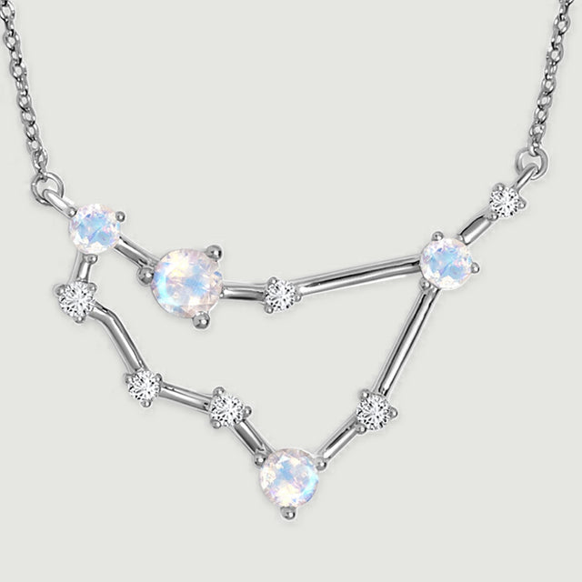 The silver pendant has polished connecting bars and small clear stones between its larger round stones.