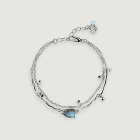 A silver bracelet forms an oval with a rough blue-flashing centre stone, curved links and an adjustable clasp.