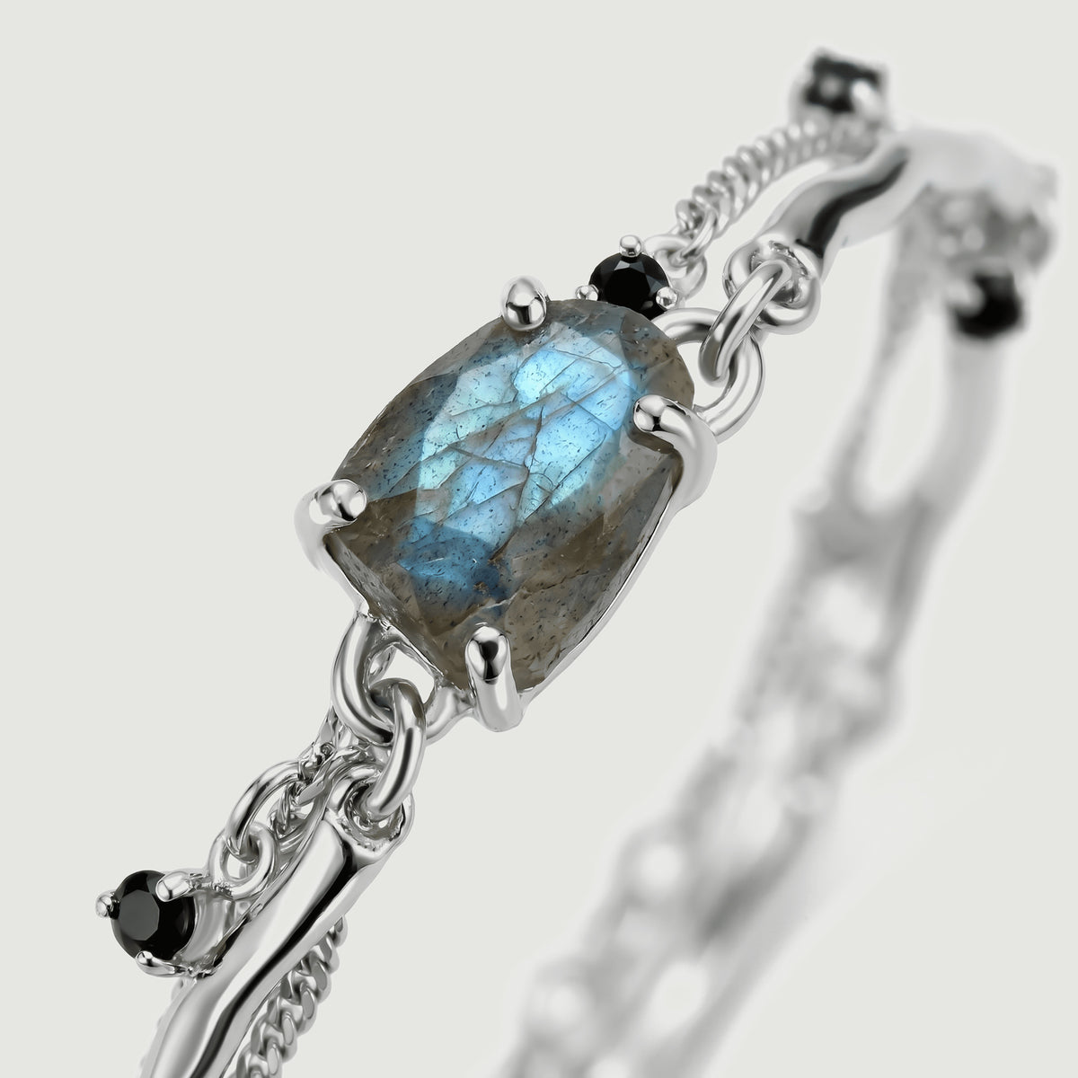 The silver prong setting and side links surround a blue-flashing labradorite stone in a diagonal close view.