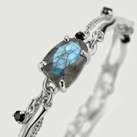 The silver prong setting and side links surround a blue-flashing labradorite stone in a diagonal close view.