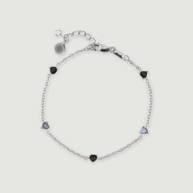 A sterling silver chain bracelet forms an oval with alternating black and blue gray heart shaped stones.
