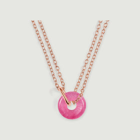 A glossy pink quartz circle is suspended from a rose gold connector and double chain on light gray.