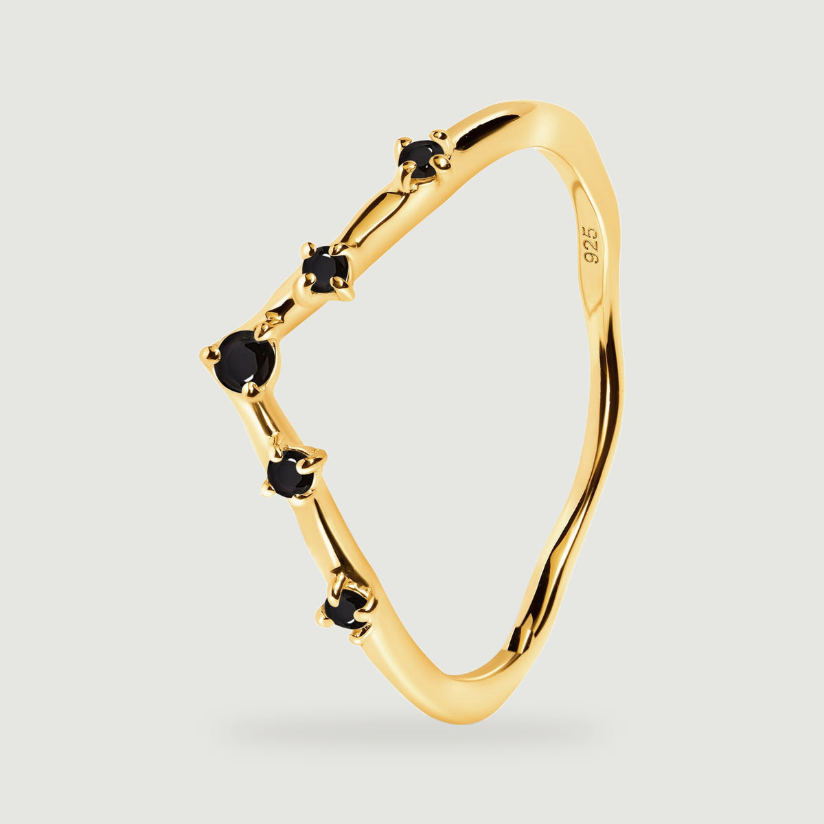 An angled yellow gold ring reveals its slim band and raised settings for five black stones.
