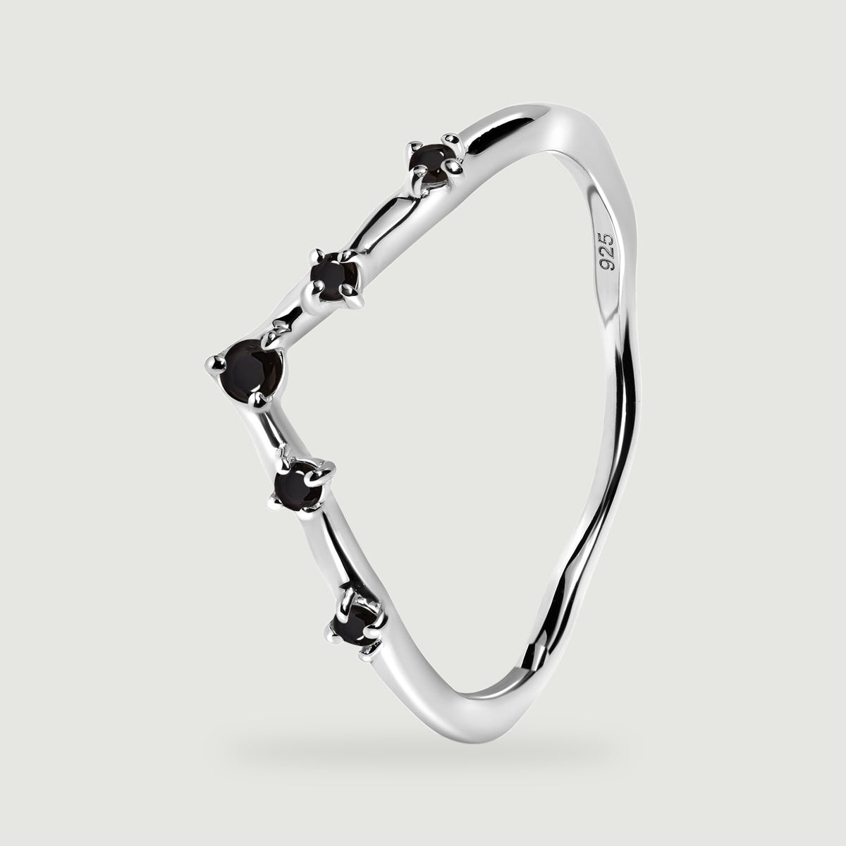 The silver ring stands at an angle with its open interior and black stone settings visible.