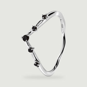 The silver ring stands at an angle with its open interior and black stone settings visible.
