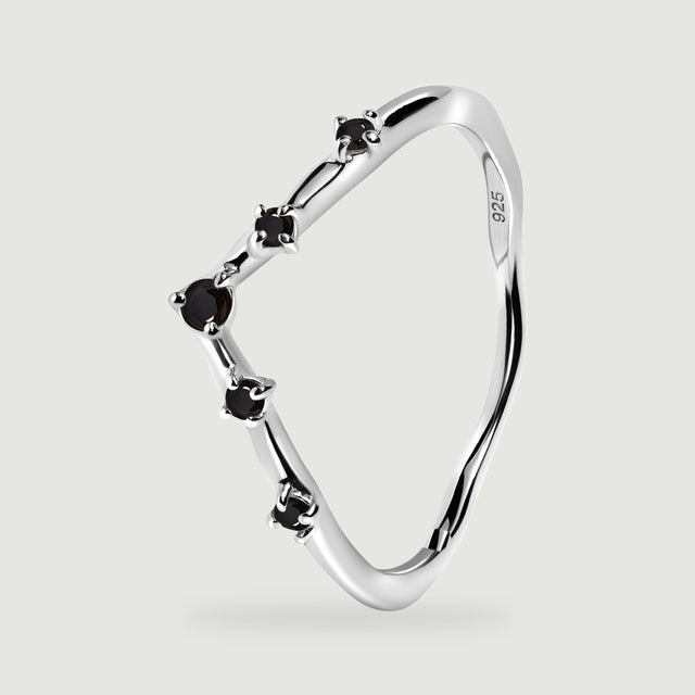 The silver ring stands at an angle with its open interior and black stone settings visible.