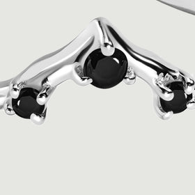 A close view shows the central black stone and the surrounding polished silver prongs.