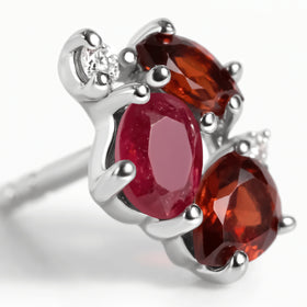 A sterling silver gemstone stud fills the frame with polished prongs, a pink centre stone and deep red facets.