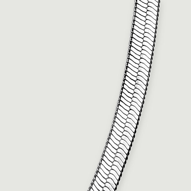 The rising right side of the flat chain shows its slim edge and reflective link pattern.