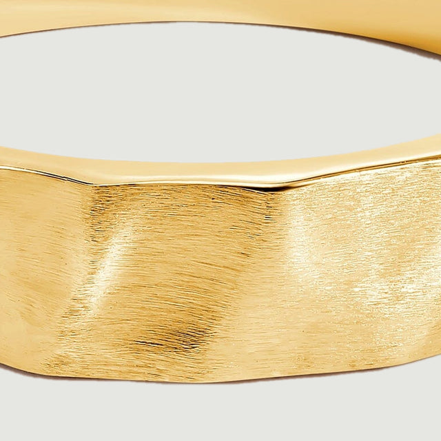 A close view shows the brushed grain and shallow facets across the yellow gold band.