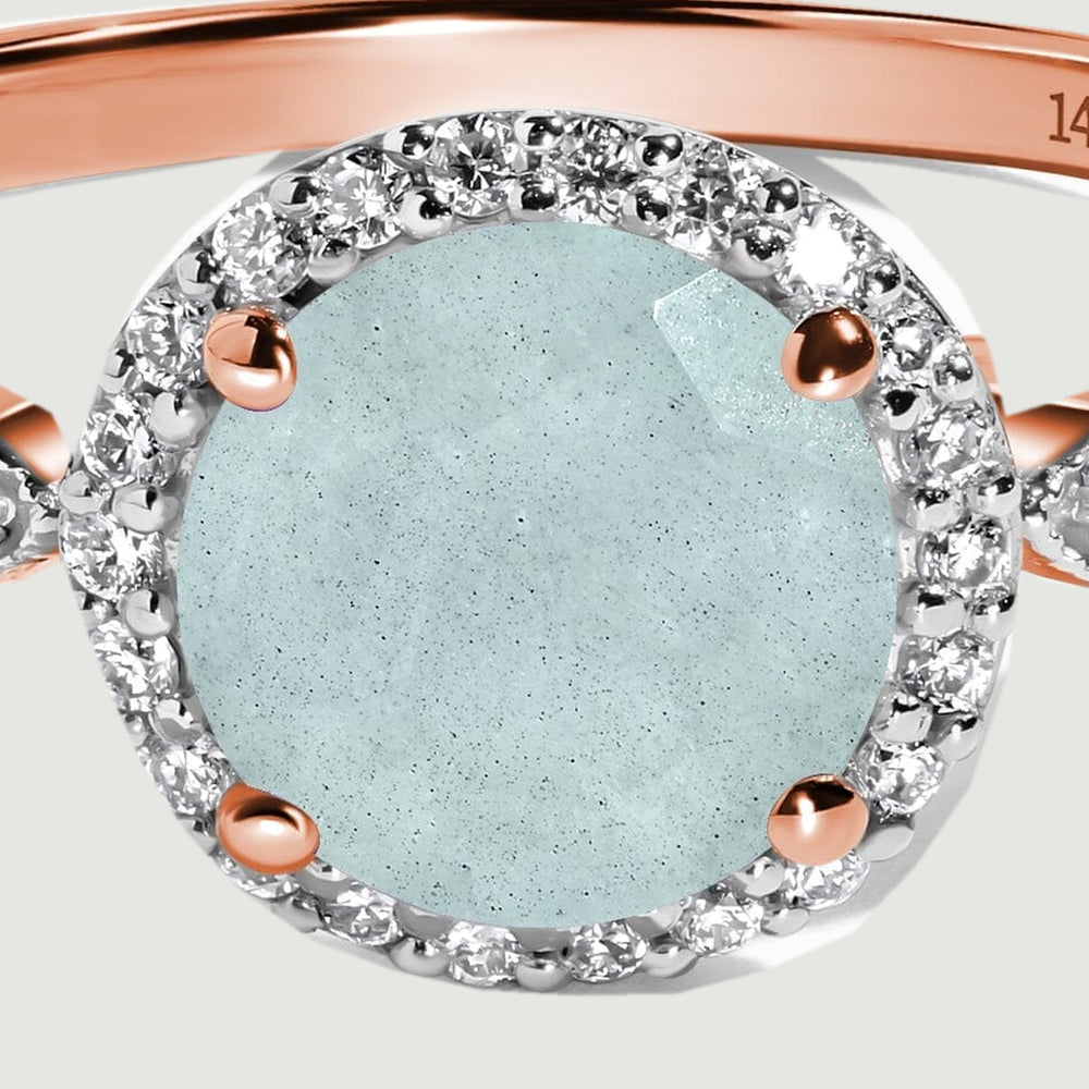 Four rose gold prongs frame the oval aquamarine inside a closely set diamond halo.
