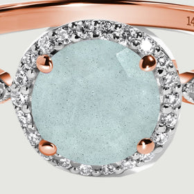 Four rose gold prongs frame the oval aquamarine inside a closely set diamond halo.