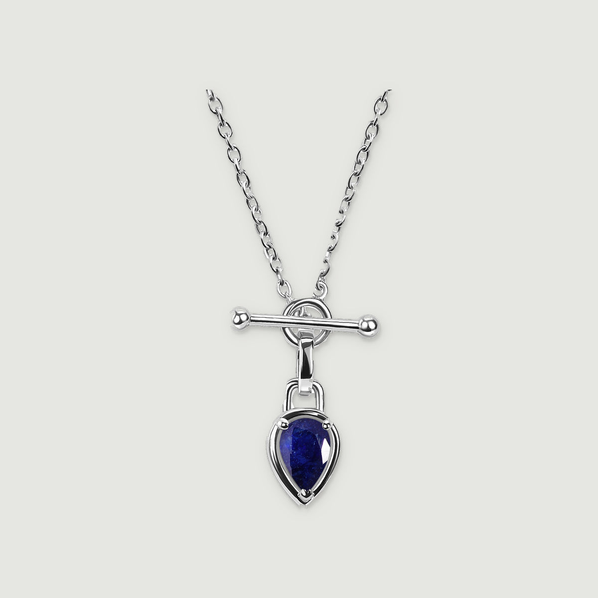 A silver-tone necklace with a deep blue pear-shaped pendant rests on a light gray background.