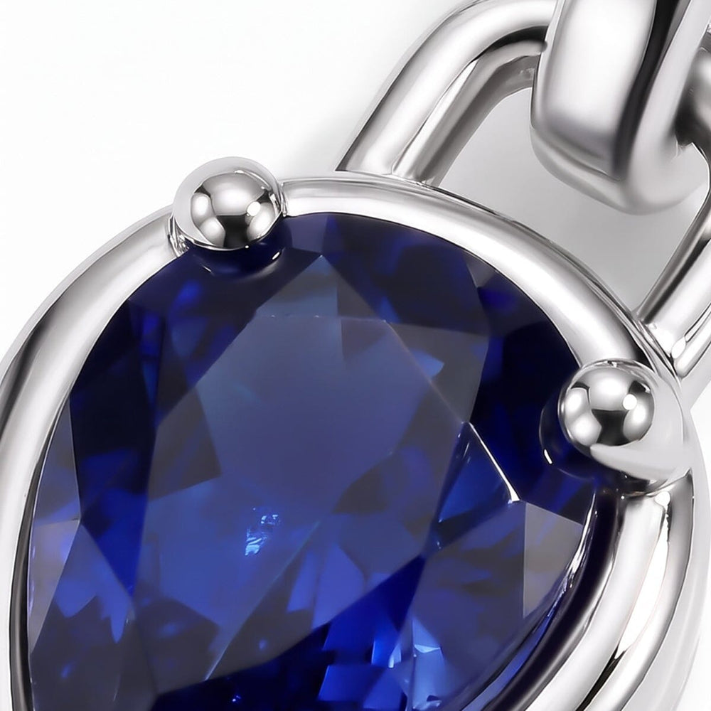 Blue sapphire facets and rounded silver-tone prongs fill this close-up view.