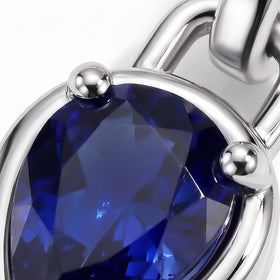 Blue sapphire facets and rounded silver-tone prongs fill this close-up view.