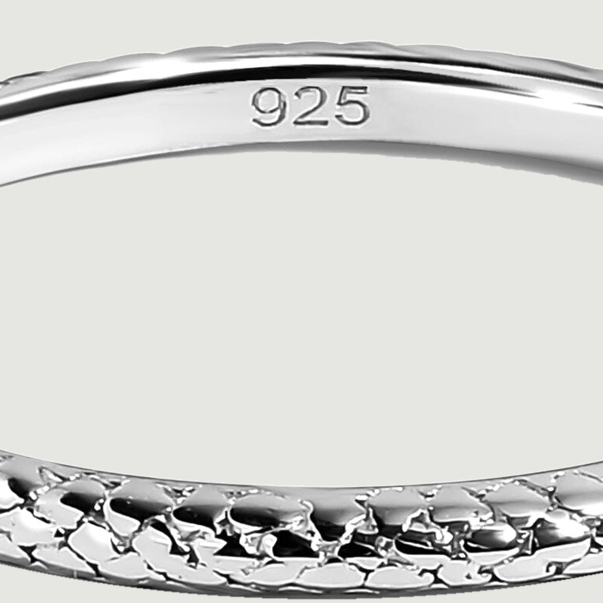 The smooth inner surface of a silver ring bears a 925 purity stamp above the textured front edge.
