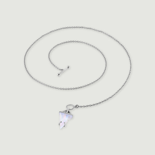 A sterling silver necklace lies in a loose coil with a triangular moonstone pendant and a polished toggle clasp on pale gray.