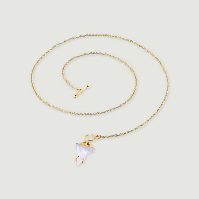 A yellow gold vermeil chain curves around a pointed moonstone pendant and a separate rounded toggle bar on a light gray surface.