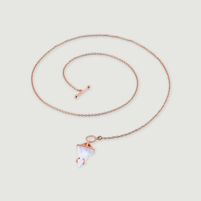 A rose gold vermeil necklace rests in an open coil, showing its linked chain and pale triangular moonstone on gray.