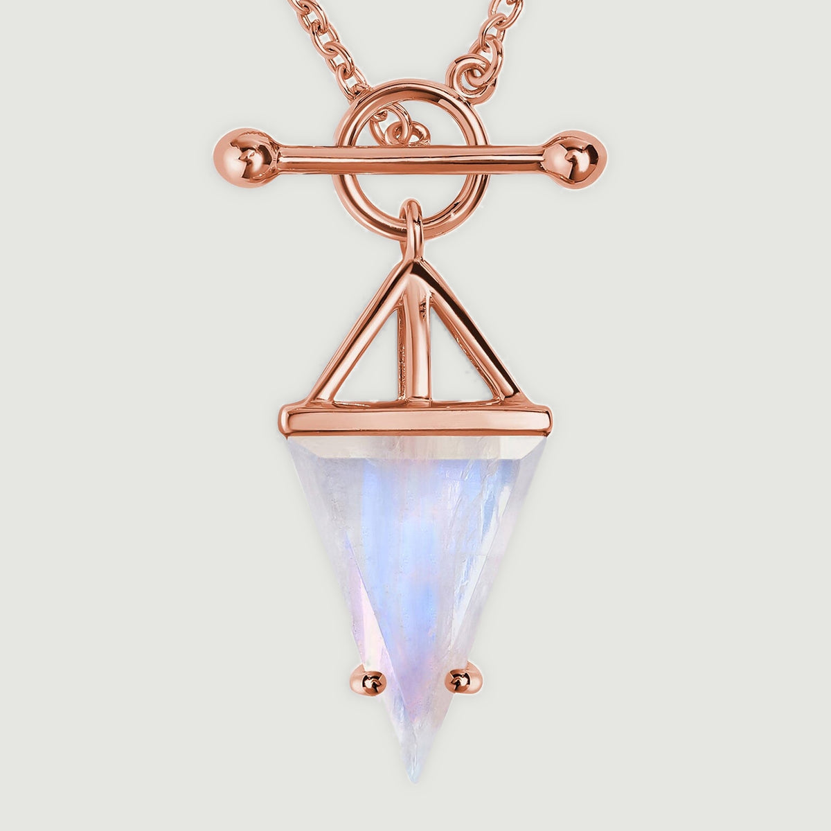 A rose gold vermeil toggle and open triangular setting frame a pointed moonstone in this close detail.