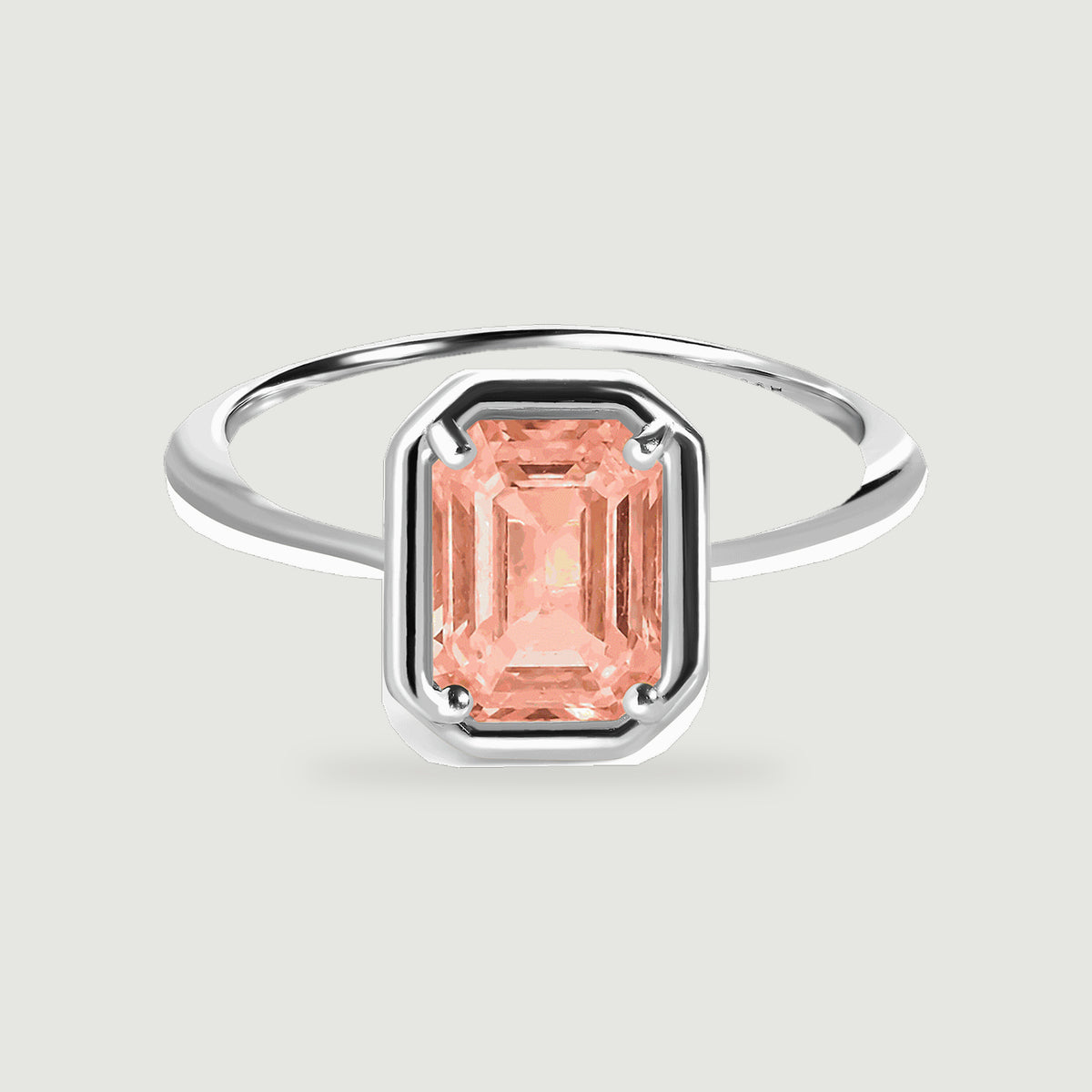 A sterling silver ring with a rectangular peach coral stone is centered on a light gray background.