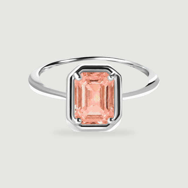 A sterling silver ring with a rectangular peach coral stone is centered on a light gray background.