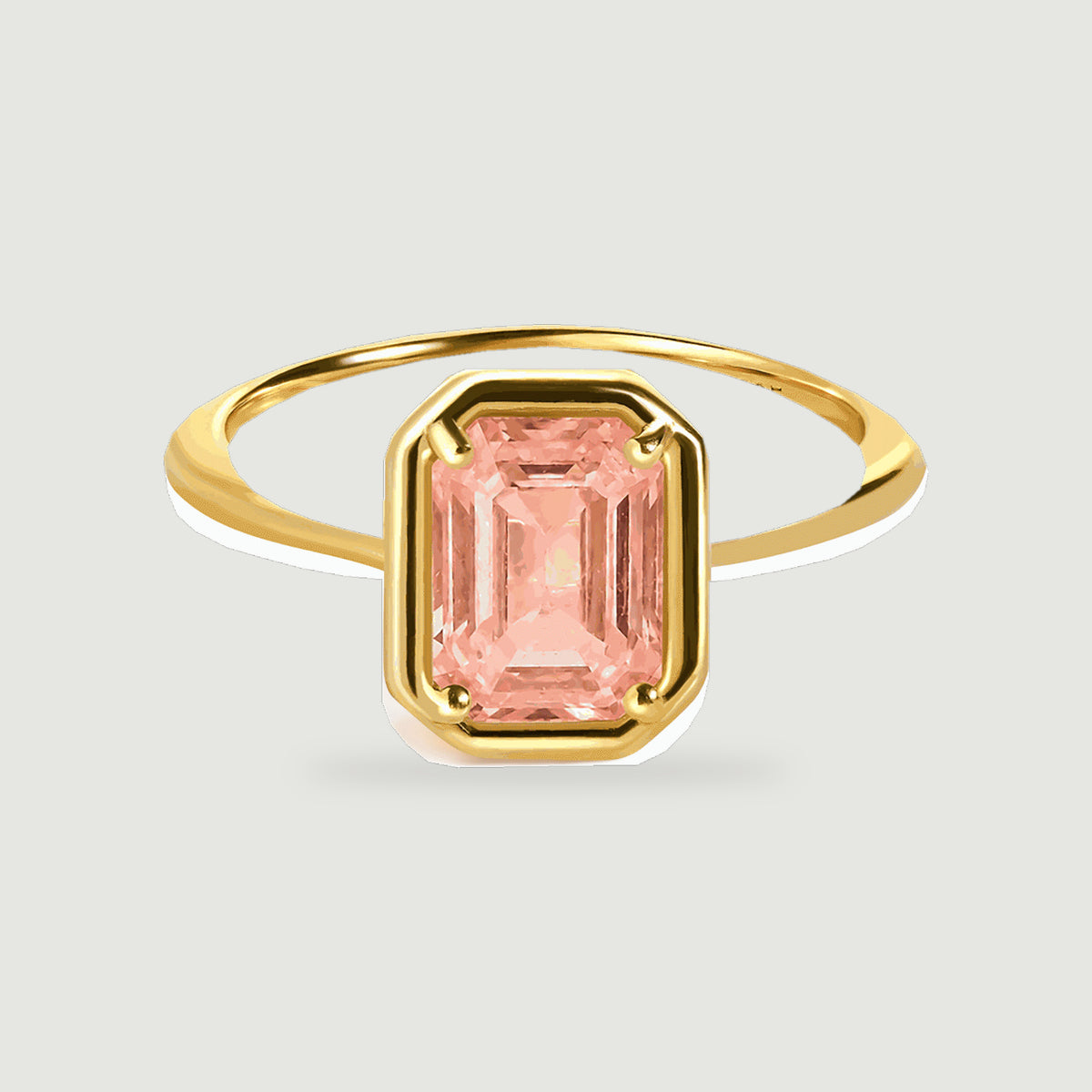 A yellow gold vermeil ring displays a peach coral step cut stone held by four rounded prongs.