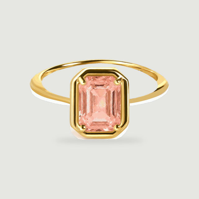 A yellow gold vermeil ring displays a peach coral step cut stone held by four rounded prongs.