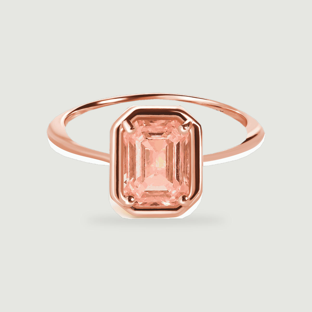 A rose gold vermeil ring shows its slim polished band and rectangular coral colored center stone.