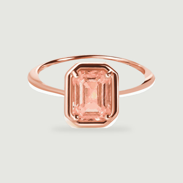A rose gold vermeil ring shows its slim polished band and rectangular coral colored center stone.