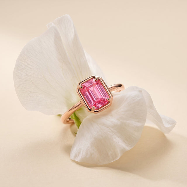 A rose gold vermeil ring with a pink rectangular stone is nestled between ivory flower petals.