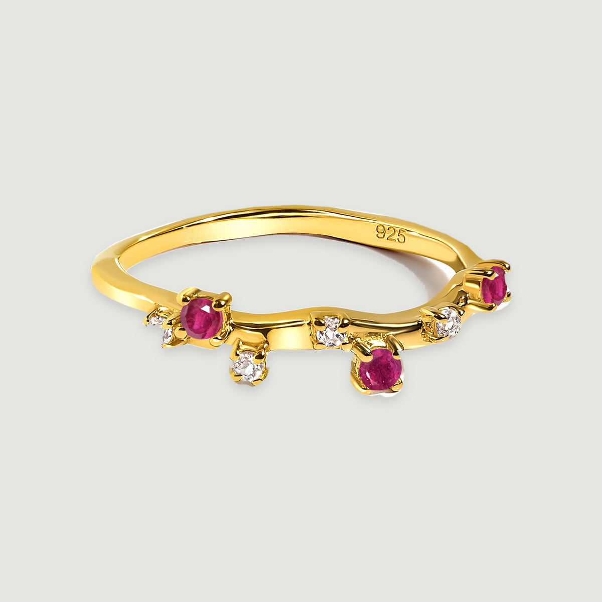 Three pink-red stones and small clear accents follow the wavy yellow gold vermeil band.
