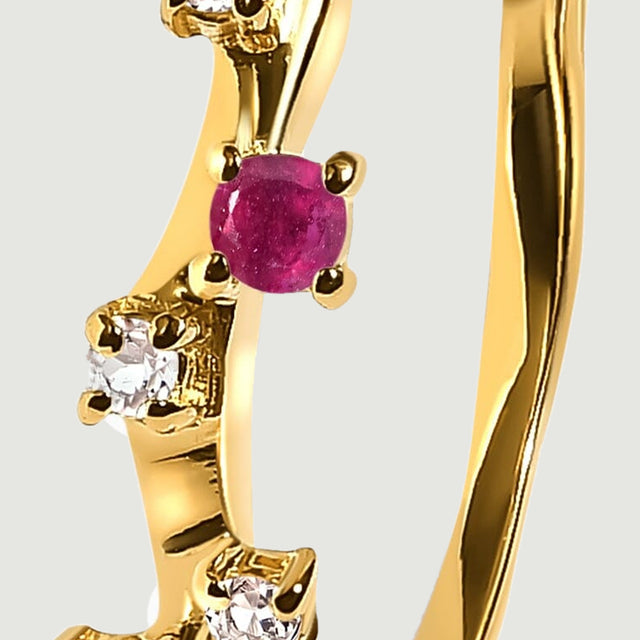 A faceted clear stone sits beside a round pink-red stone on the curved yellow gold vermeil band.