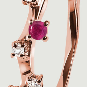 The round pink-red stone is held by rose gold vermeil prongs beside smaller clear stones.