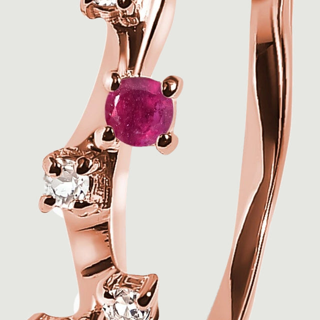 The round pink-red stone is held by rose gold vermeil prongs beside smaller clear stones.