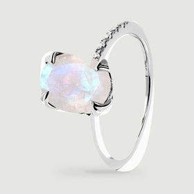 An angled sterling silver ring reveals its curved band, raised moonstone setting, and rows of clear stones.