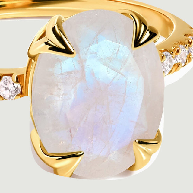 Warm gold prongs frame a pale moonstone with blue reflections beside a line of clear stones.
