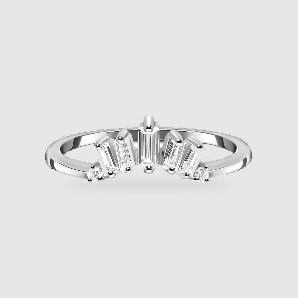A sterling silver ring is centered on a pale gray surface with its polished band and clear stone setting visible.