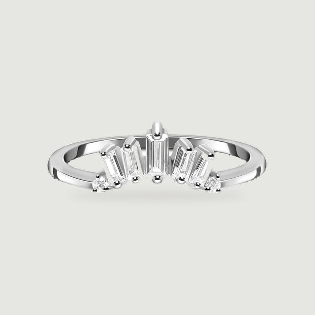 A sterling silver ring is centered on a pale gray surface with its polished band and clear stone setting visible.