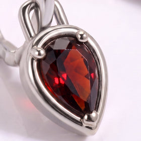 A close view shows dark red garnet facets, a bright silver-tone setting, and the curved hoop.