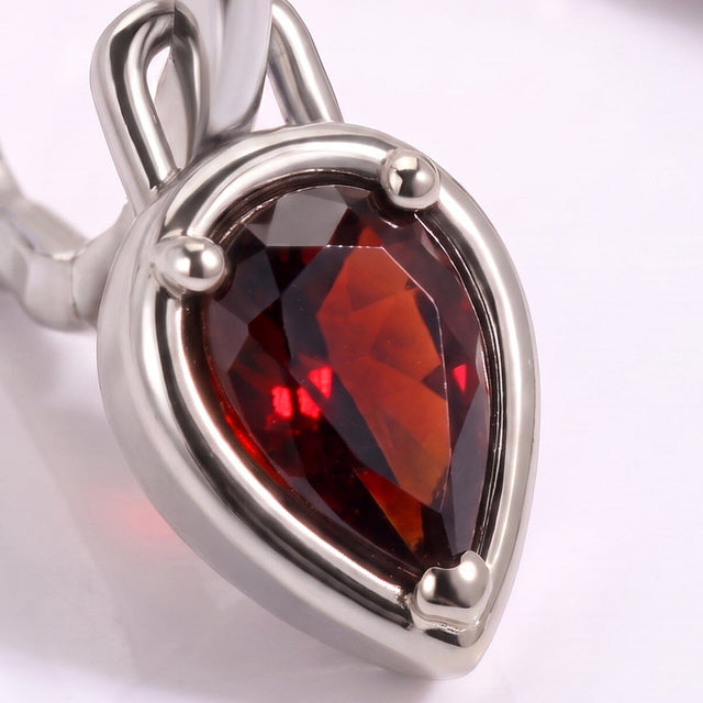 A close view shows dark red garnet facets, a bright silver-tone setting, and the curved hoop.