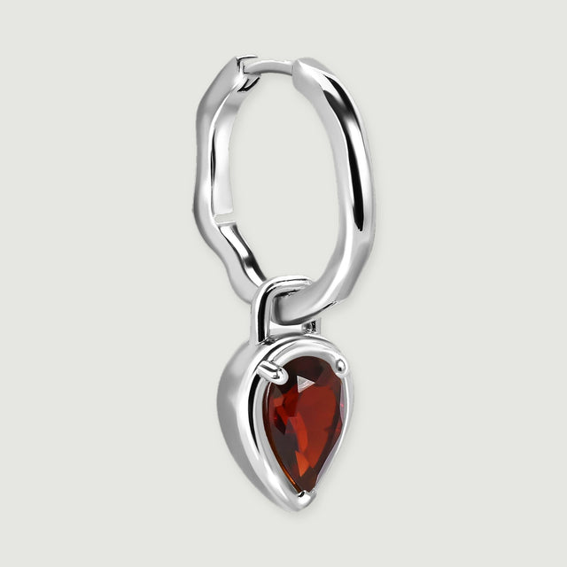 A single silver-tone hoop is angled to show its hinge, curved band, and the depth of its garnet drop.