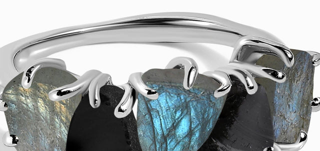 A close view shows the curved silver-tone band and upper claws above blue-gray and black raw stones.