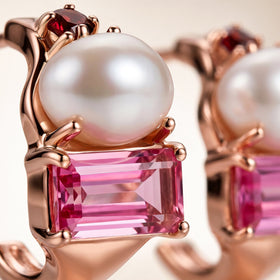 An enlarged view highlights the pearl surface, pink stone facets and warm rose gold-tone setting.